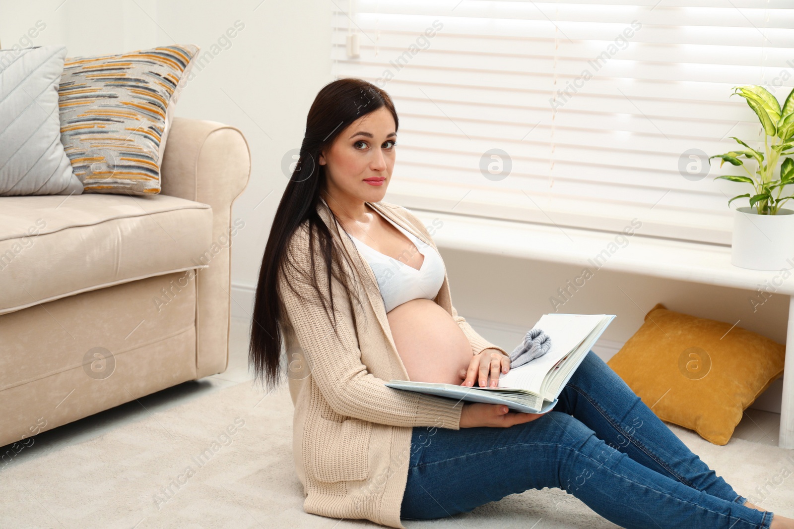 Photo of Beautiful pregnant woman with memory book at home