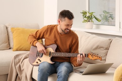 Man learning to play guitar with online music course at home. Time for hobby