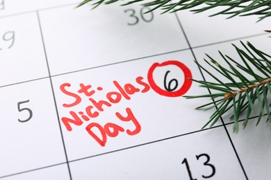 Photo of Fir tree branch on calendar page with marked date, closeup. December, 6 - Saint Nicholas Day