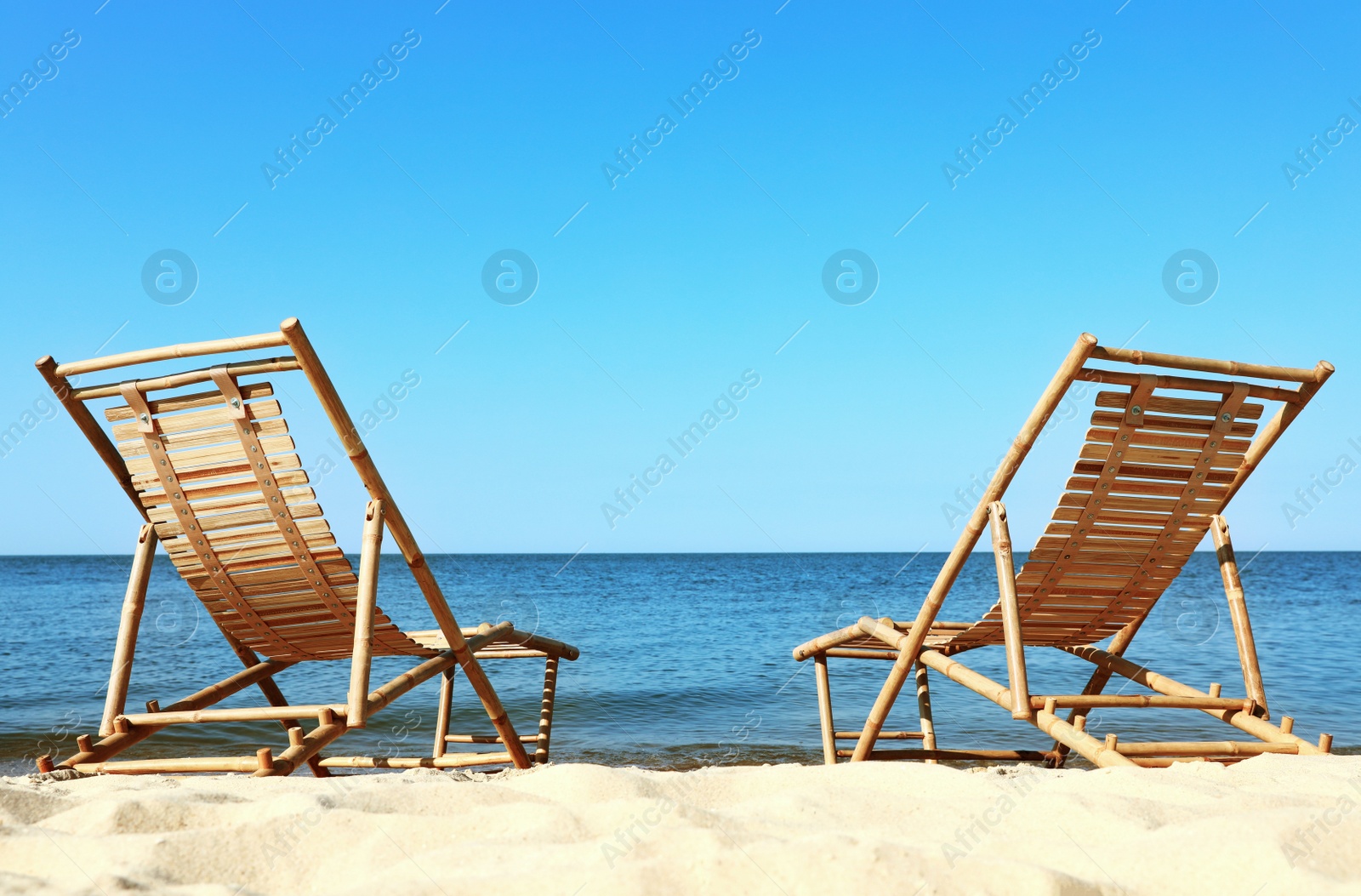 Photo of Sandy beach with empty wooden sunbeds on sunny day