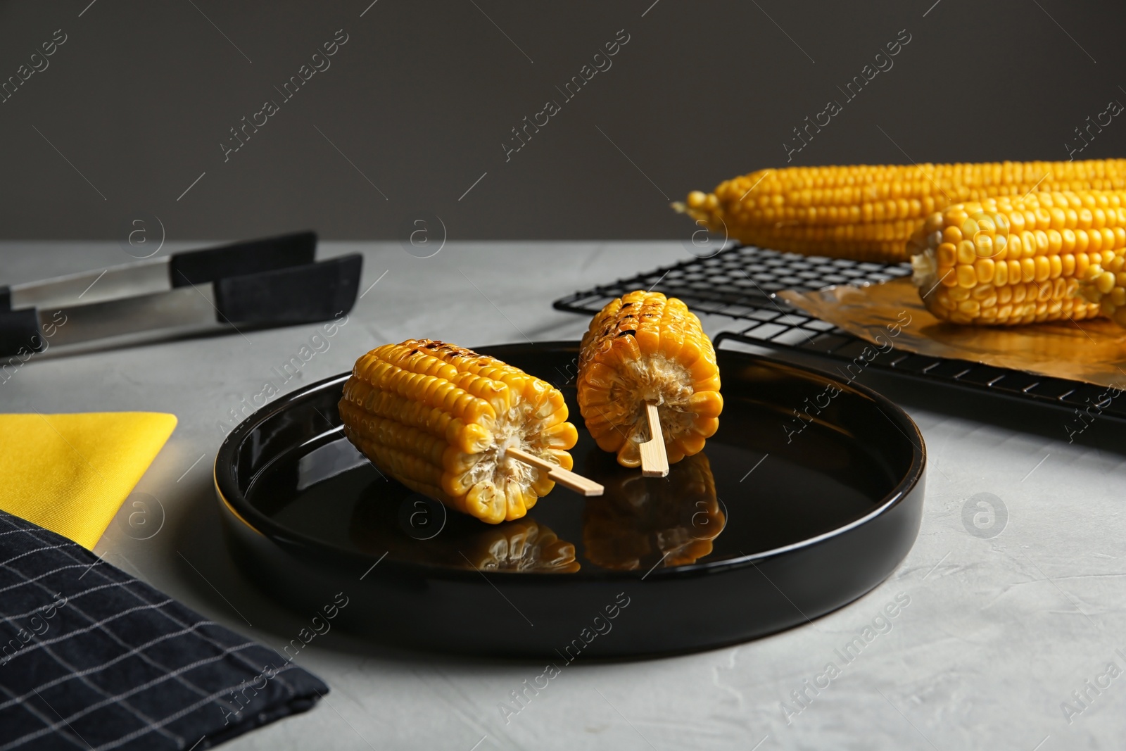 Photo of Ceramic plate with grilled corn cobs on light table