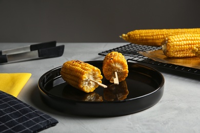 Ceramic plate with grilled corn cobs on light table