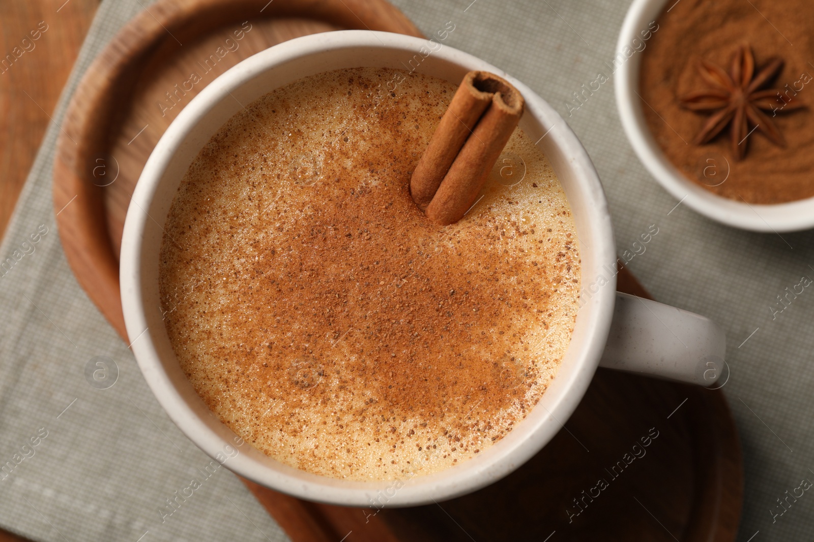 Photo of Delicious eggnog with anise and cinnamon on wooden table, top view