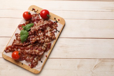 Photo of Slices of tasty fried bacon with different spices and tomatoes on wooden table, top view. Space for text