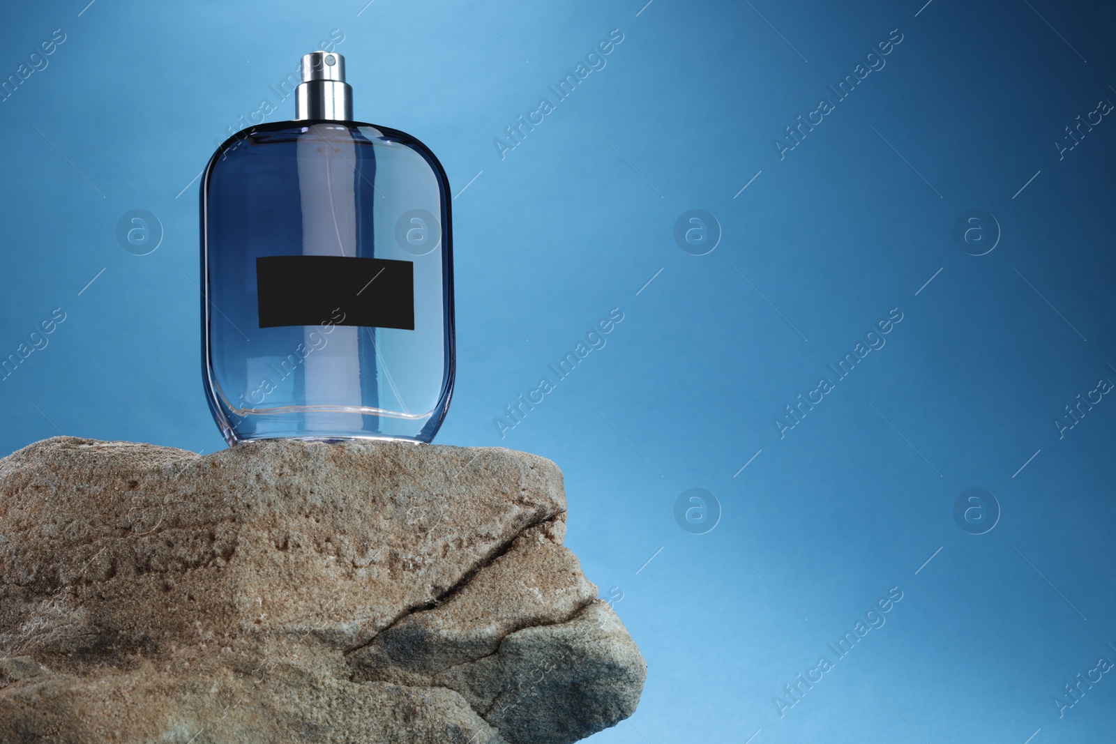 Photo of Stylish presentation of luxury men`s perfume on stone against light blue background. Space for text