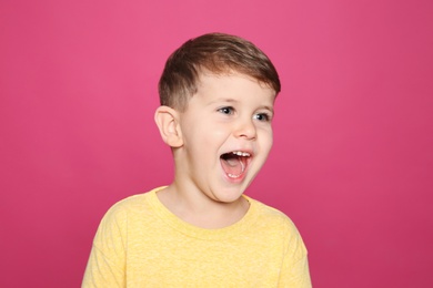 Photo of Portrait of little boy laughing on color background