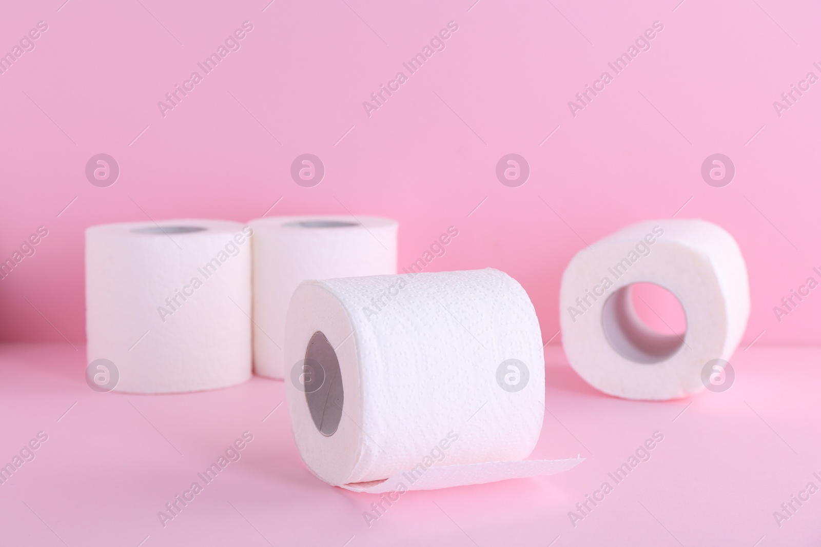 Photo of Soft toilet paper rolls on pink background, closeup