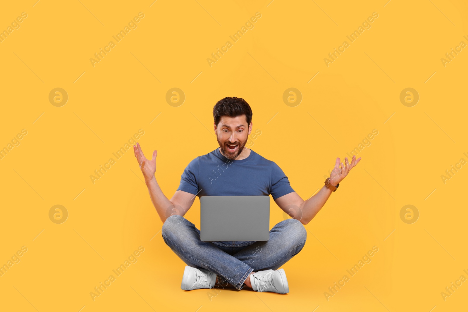 Photo of Emotional man with laptop on yellow background