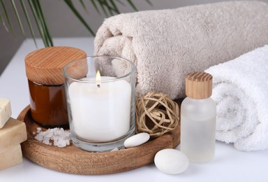 Composition with spa supplies on white table and palm leaf