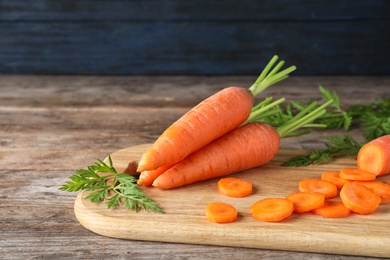 Photo of Board with cut carrot on wooden background. Space for text