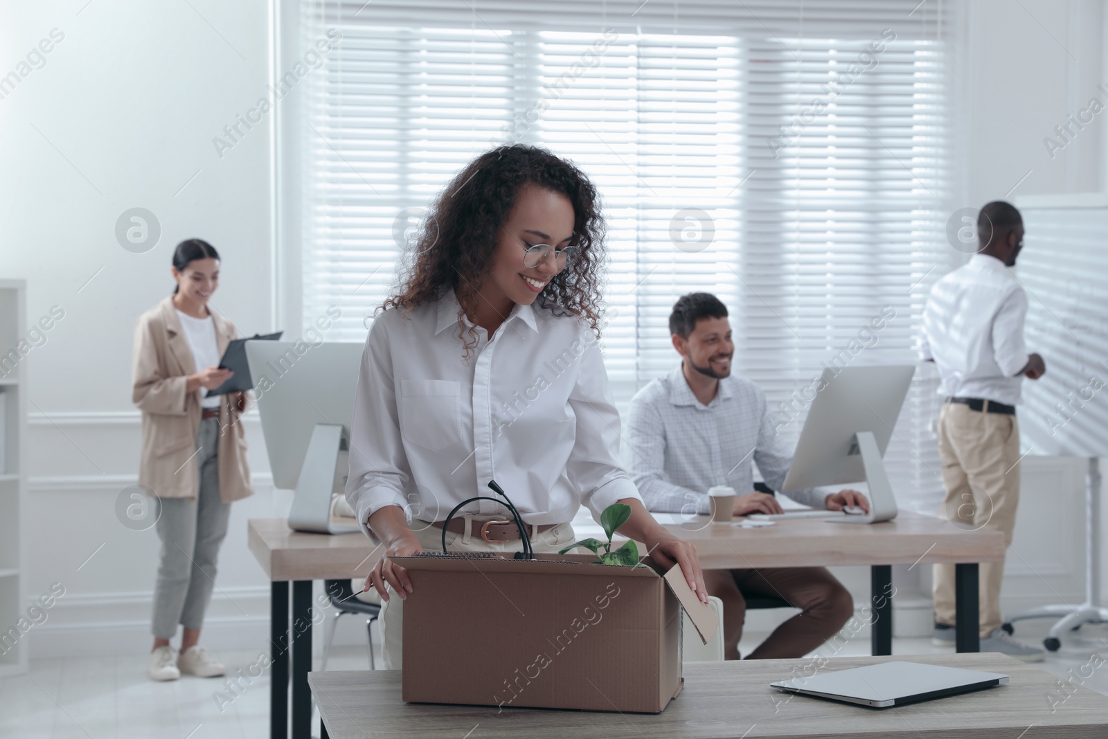 Photo of New coworker unpacking box with personal items at workplace in office