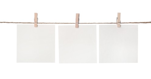 Photo of Clothespins with empty notepapers on string against white background. Space for text