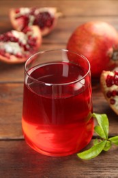 Photo of Tasty pomegranate juice in glass and fresh fruits on wooden table, closeup