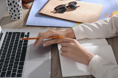 Photo of Woman with laptop planning trip at home, closeup. Summer vacation