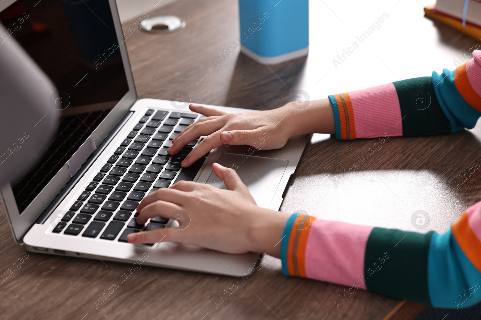 Photo of E-learning. Girl using laptop during online lesson at table indoors, closeup