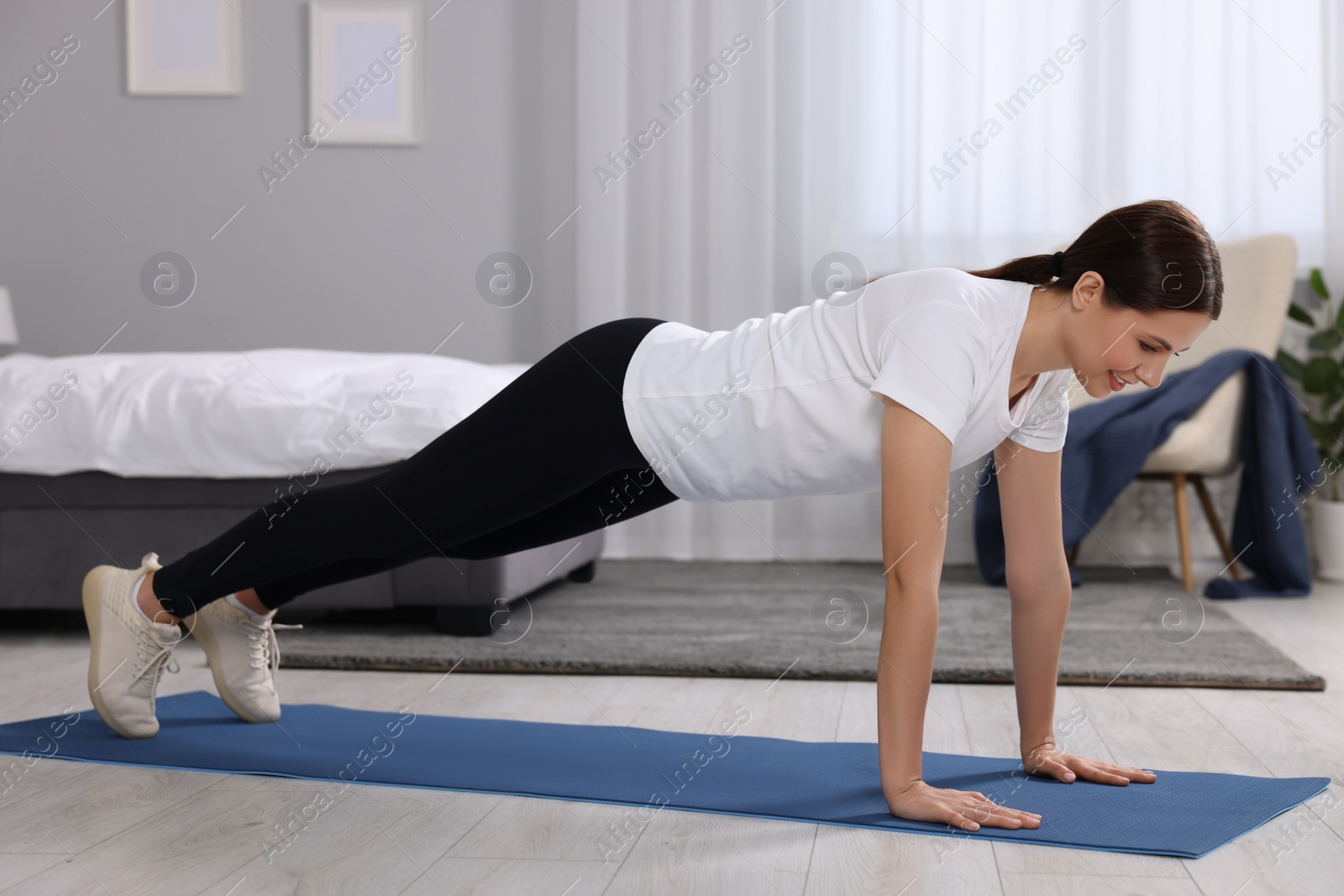 Photo of Happy woman doing plank exercise at home. Morning routine