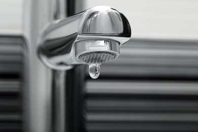 Image of Water drop falling down from tap in bathroom, closeup