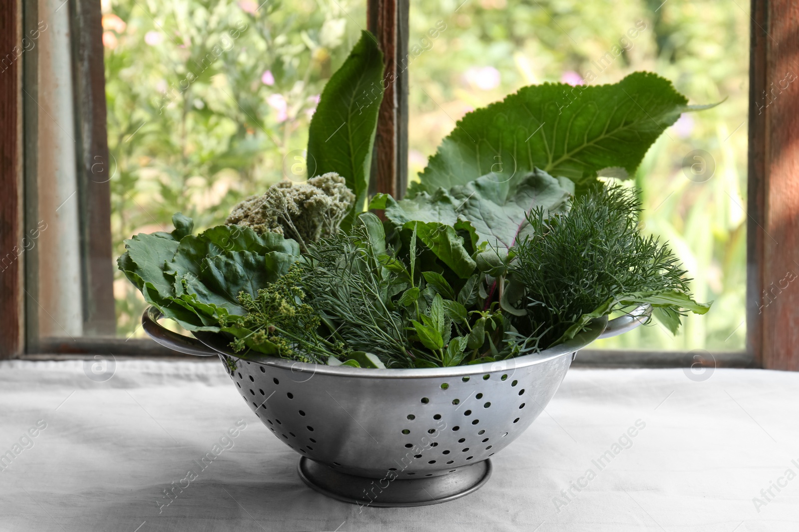 Photo of Different herbs in colander near window indoors