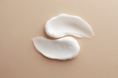 Photo of Sample facial cream on beige background, top view