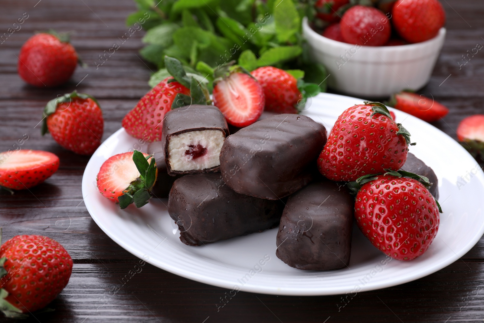 Photo of Delicious glazed curds, mint leaves and fresh strawberries on wooden table