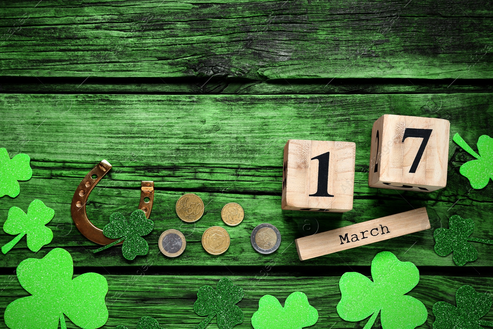 Image of Flat lay composition with clover leaves and block calendar on green wooden table, space for text. St. Patrick's Day celebration