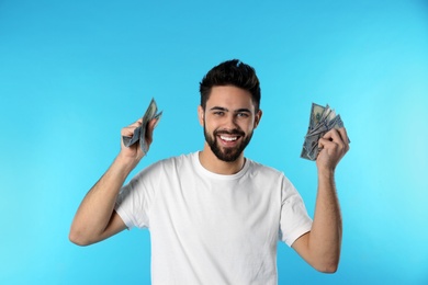 Portrait of happy young man with money on color background