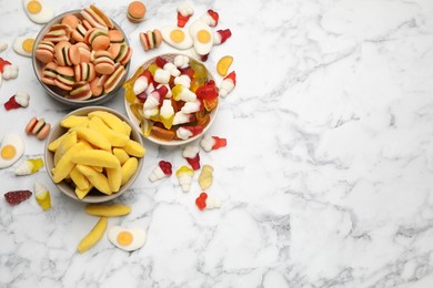 Photo of Many different delicious gummy candies on white marble table, flat lay. Space for text