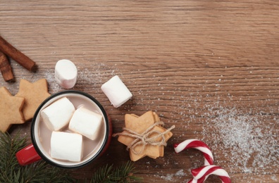 Photo of Flat lay composition with marshmallows, hot drink and sweets on wooden table. Space for text