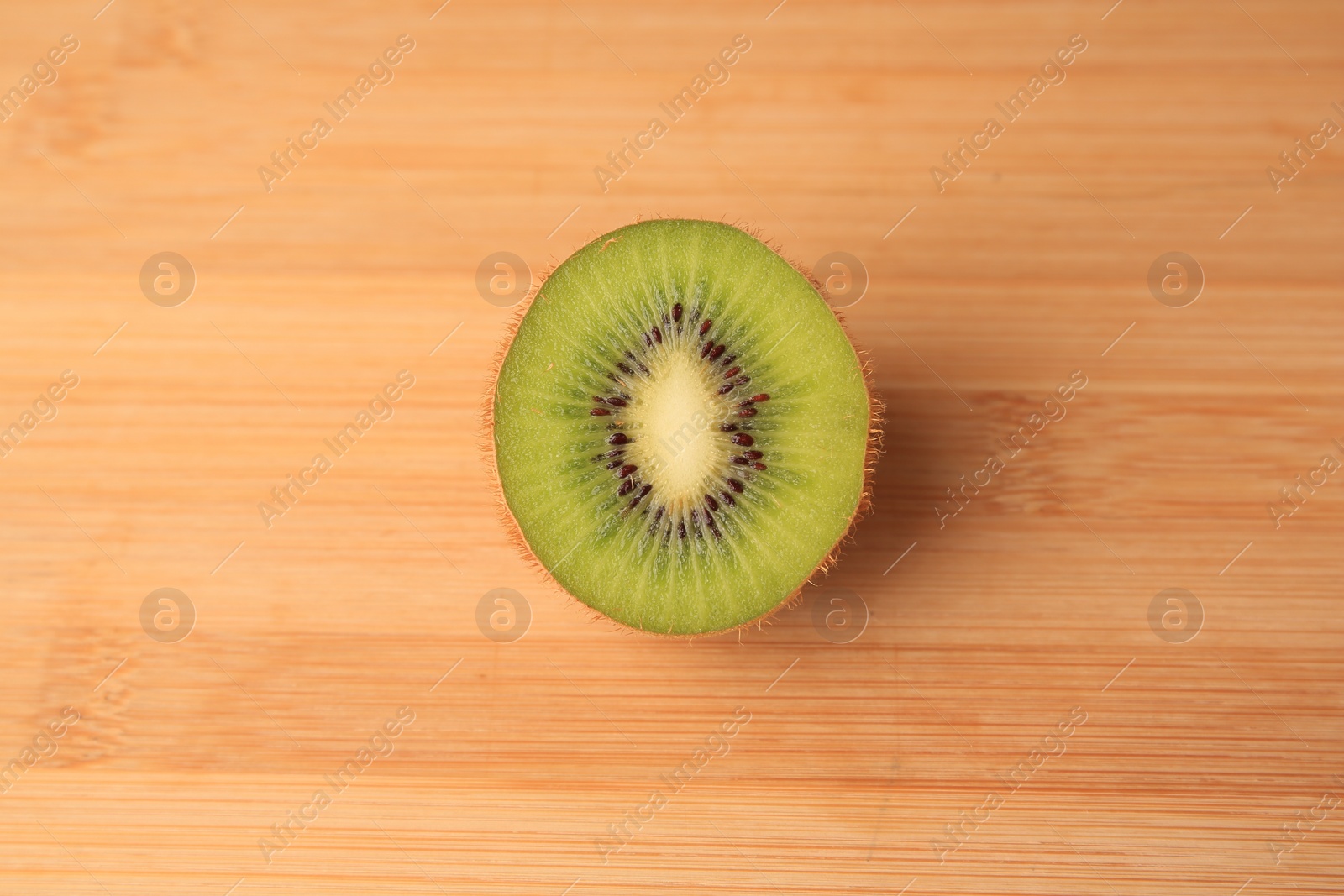 Photo of Half of fresh ripe kiwi on wooden table, top view