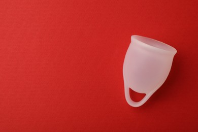 Photo of Menstrual cup on red background, top view. Space for text
