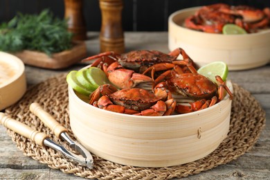 Photo of Delicious boiled crabs with lime and dill served on wooden table