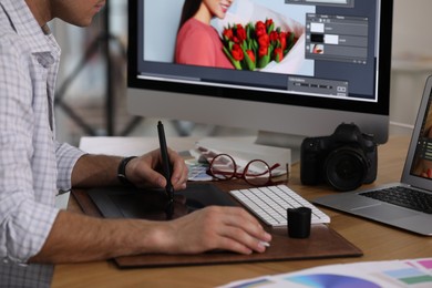 Photo of Professional retoucher working on graphic tablet at table, closeup