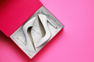 Photo of Stylish women's shoes in cardboard box on pink background, top view. Space for text