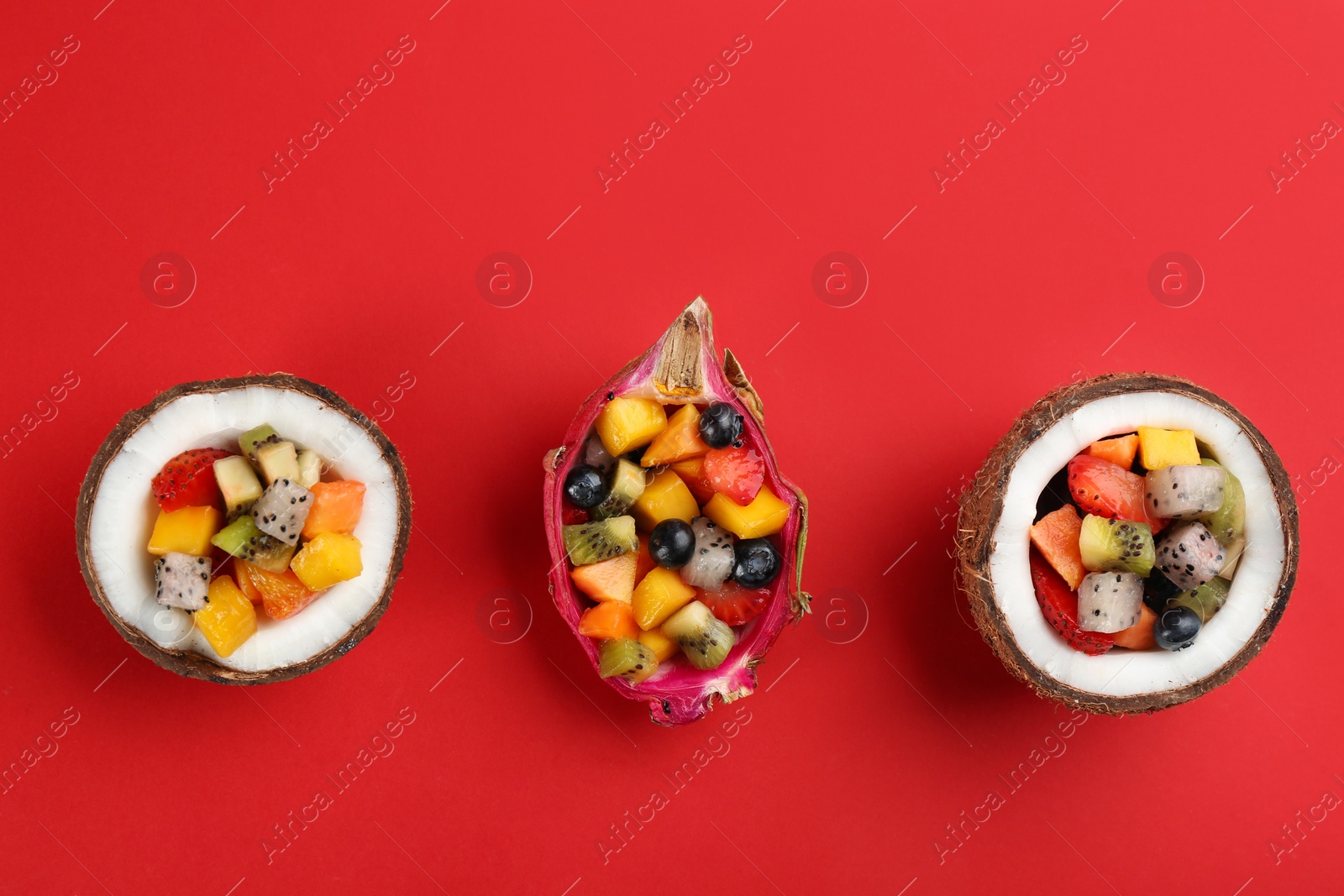Photo of Delicious exotic fruit salad on red background, flat lay