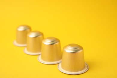 Photo of Many coffee capsules on yellow background, closeup