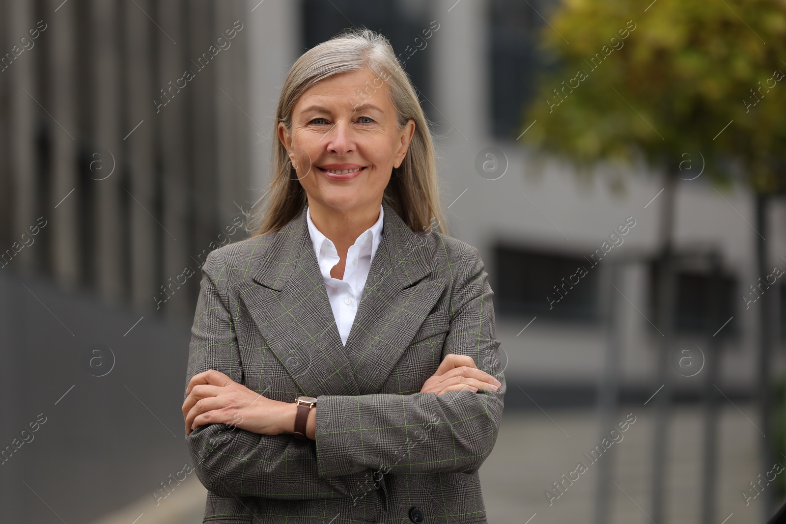 Photo of Smiling woman with crossed arms outdoors, space for text. Lawyer, businesswoman, accountant or manager