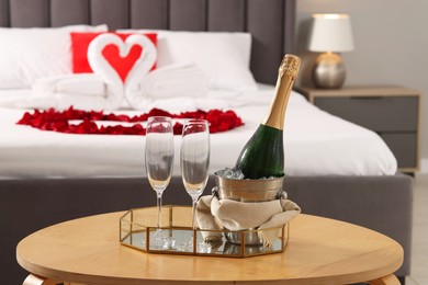 Honeymoon. Sparkling wine and glasses on wooden table in room