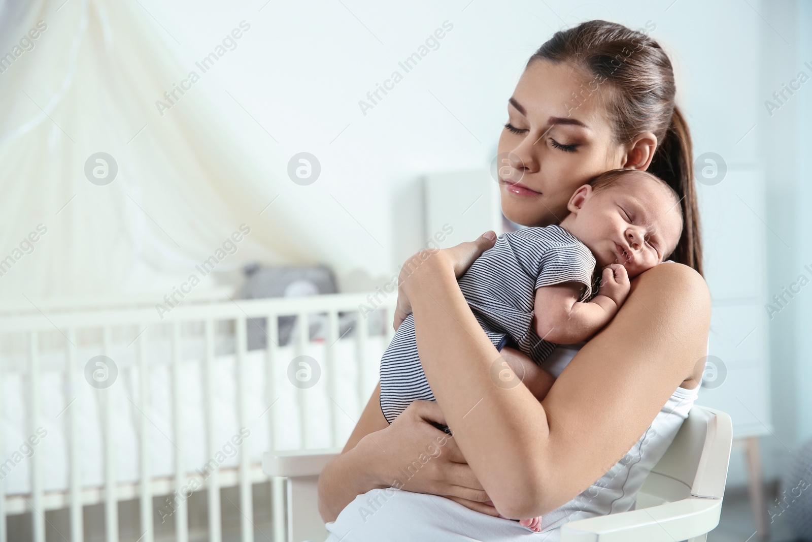 Photo of Young woman with her newborn baby at home. Space for text