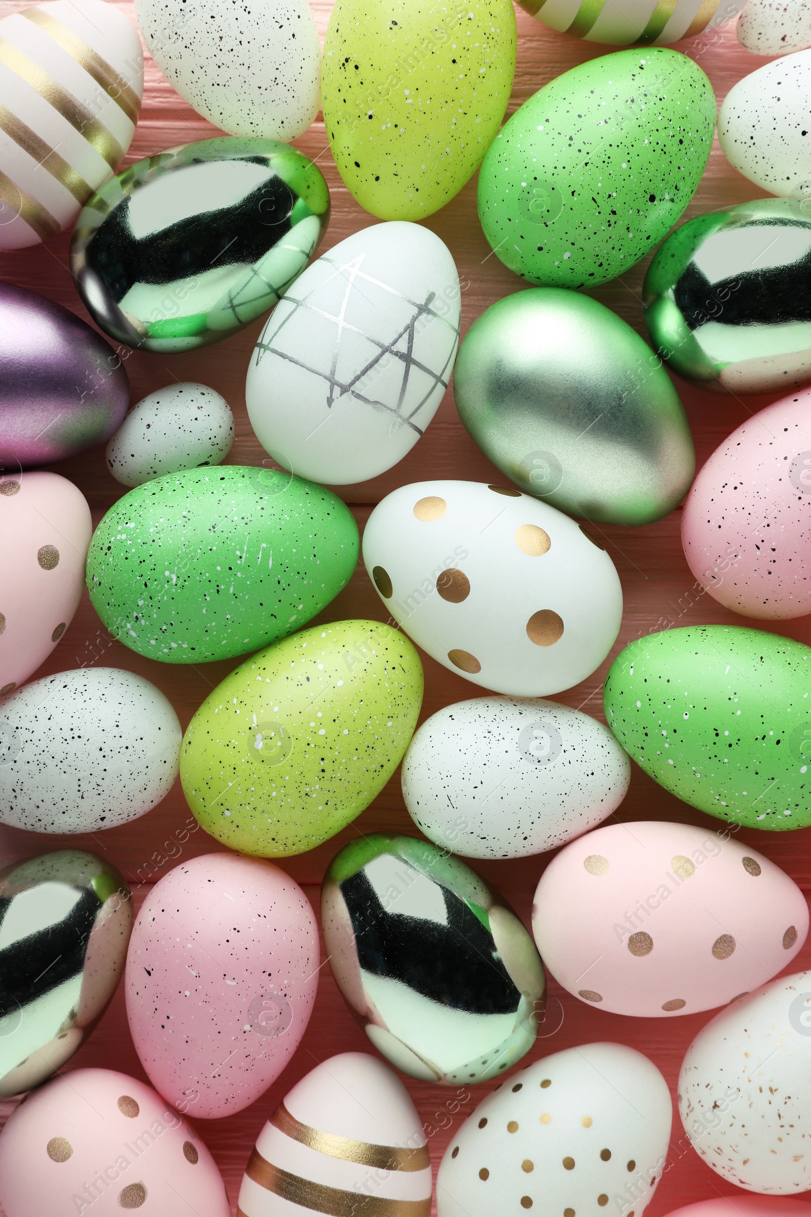 Photo of Many beautifully decorated Easter eggs on pink wooden table, flat lay