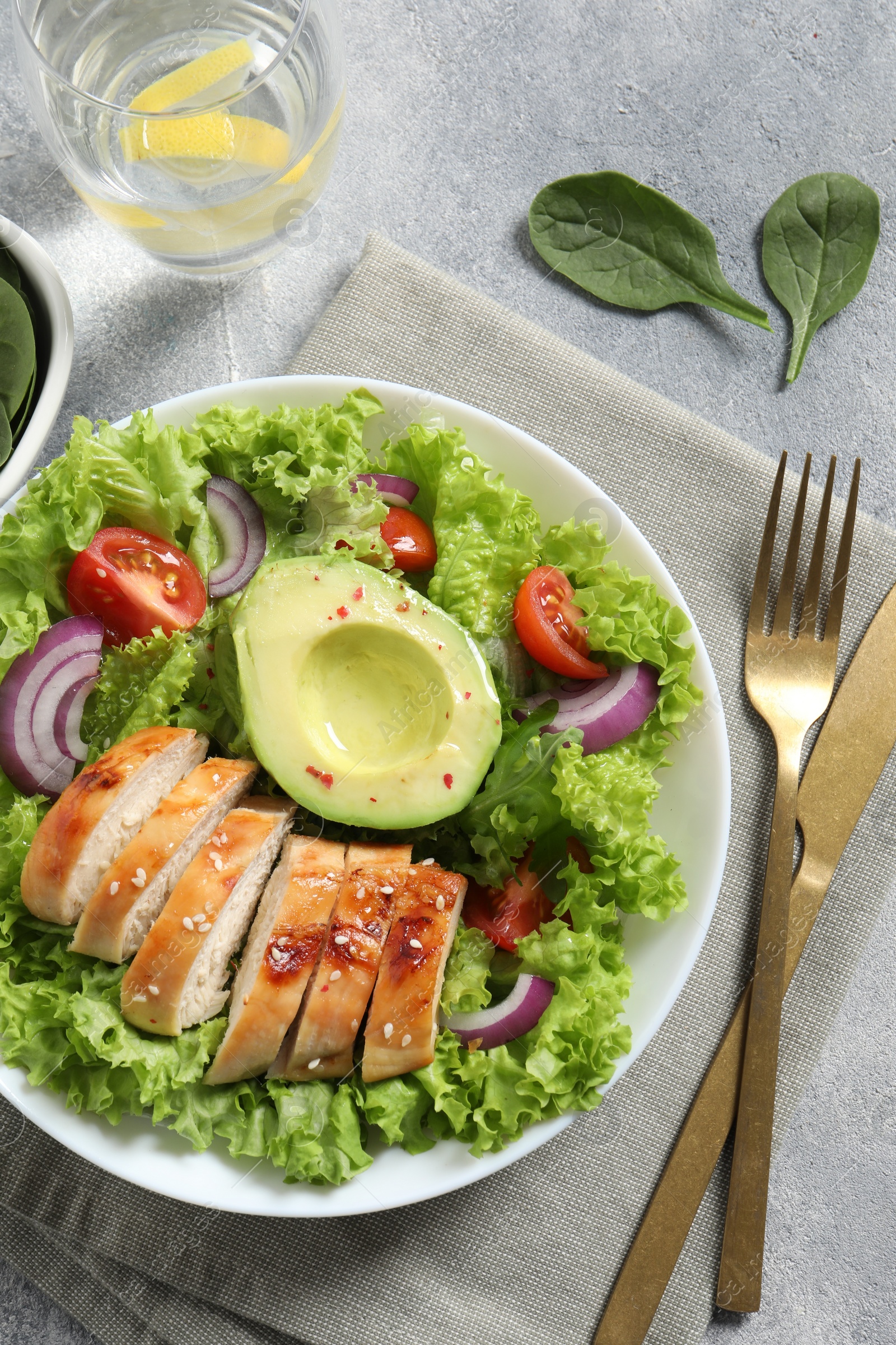 Photo of Delicious salad with chicken, avocado and vegetables served on light grey table, flat lay