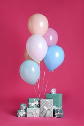 Photo of Many gift boxes and balloons near bright pink​background