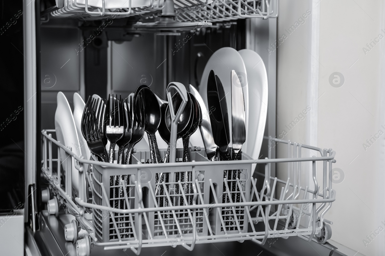 Photo of Open modern dishwasher with clean tableware, closeup