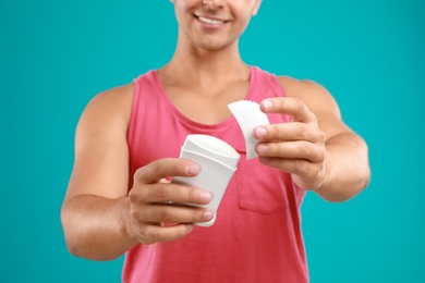 Photo of Young man holding deodorant on blue background, closeup. Mockup for design