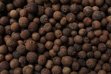 Aromatic allspice pepper grains as background, top view