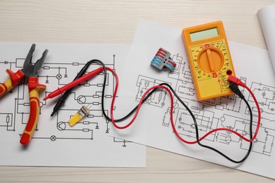 Photo of Flat lay composition with wiring diagrams and digital multimeter on white wooden table