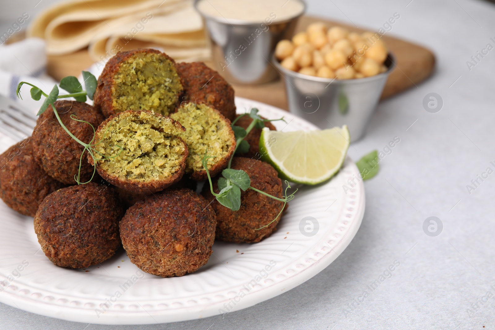 Photo of Delicious falafel balls, lime and microgreens on light table