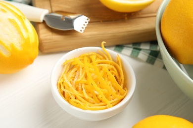 Photo of Grated lemon zest and fresh fruits on white wooden table