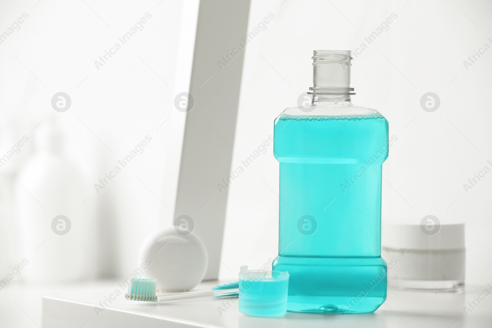 Photo of Bottle of mouthwash on white shelf in bathroom, space for text