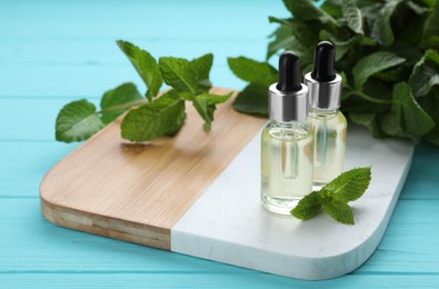 Photo of Bottles of essential oil and mint on turquoise wooden table