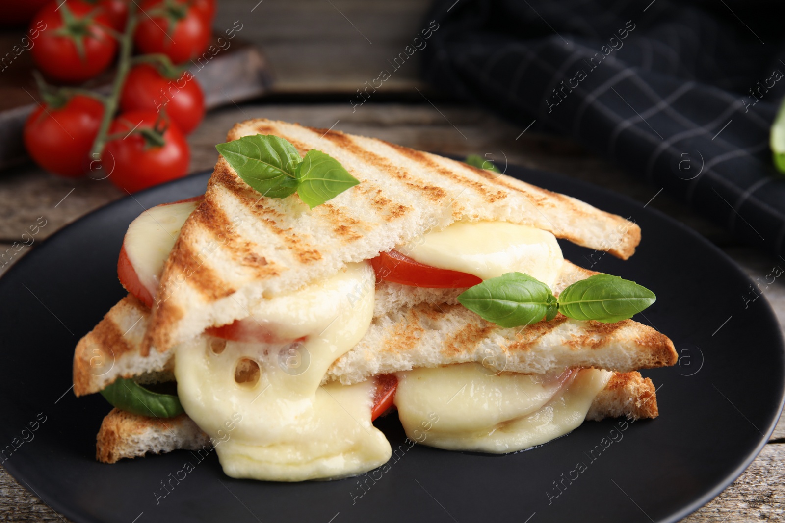 Photo of Delicious grilled sandwiches with mozzarella, tomatoes and basil on black plate, closeup